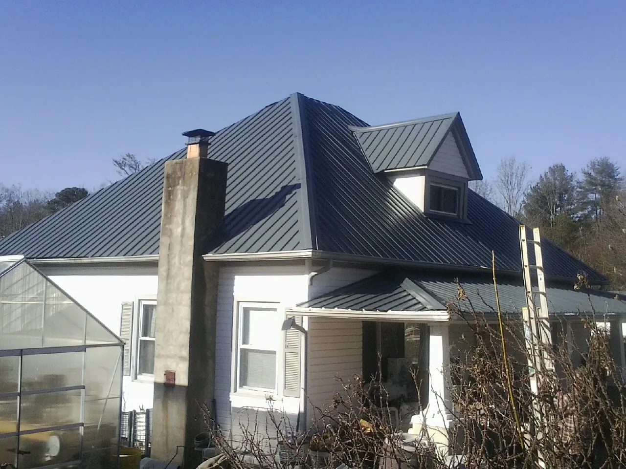 Dark blue standing seam metal roof on a white farmhouse with dormer — Slate & Tile Roof Repair by Roofing Brothers in Bandon