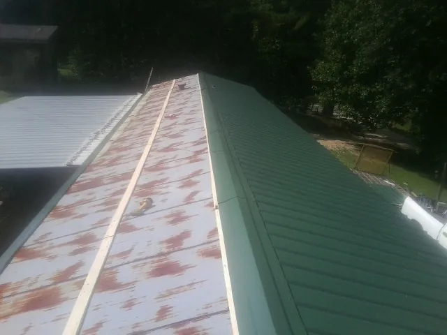 Old rusted panels beside newly installed green metal roofing — Wind Damage Roof Repair by Roofing Brothers in Bandon