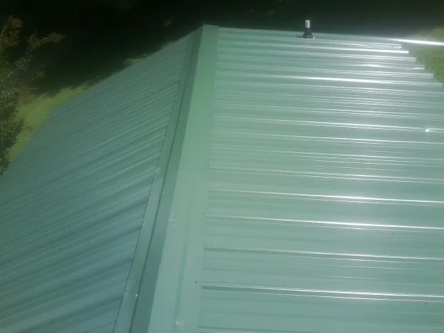 New green metal panels meeting at the ridge of a roof — Flat Roof Repair work by our crew in Bandon