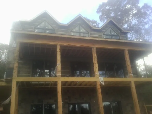 Dormers and porch framing on a large log home under construction — Roof Coating work by our crew in Bandon