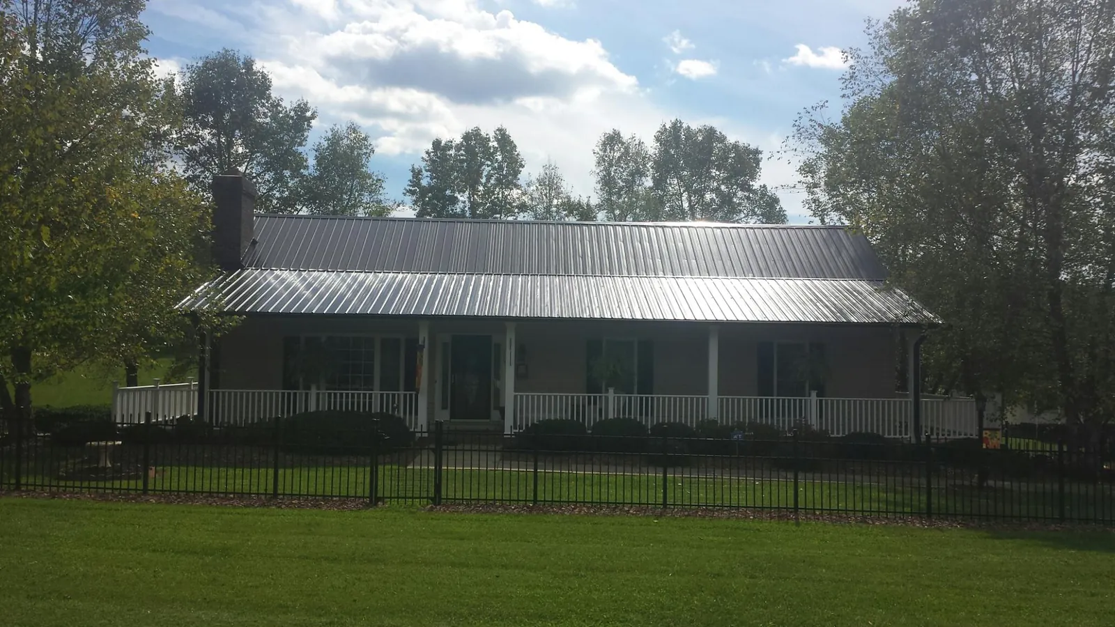 Gray metal roof on a brick ranch with a full width front porch — Gutter Guard Installation work by our crew in Bandon