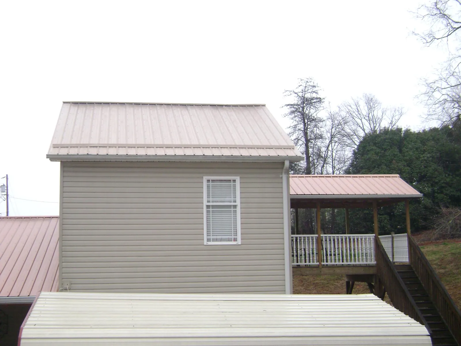 Tan metal roofs on a two story addition and attached porch, from a Roof Replacement job in Bandon