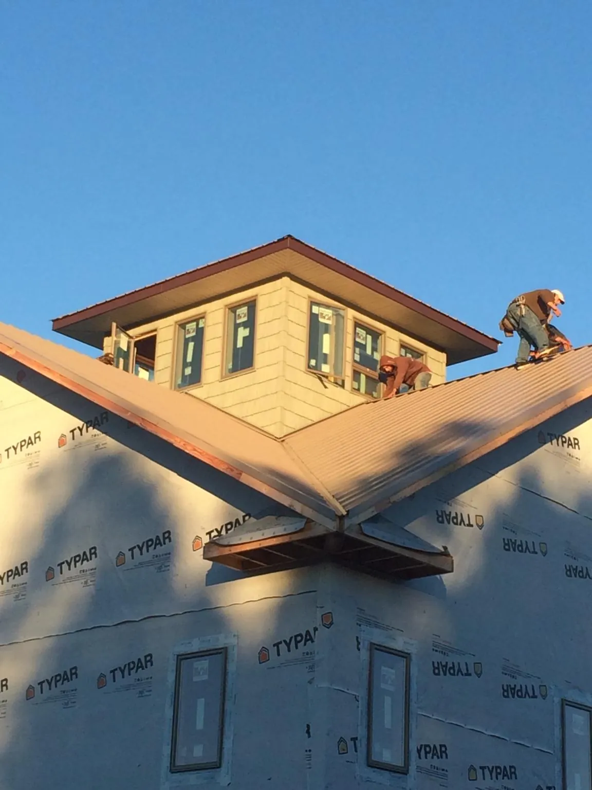 Roofers working around a rooftop cupola on a new metal roof at sunset — Roof Waterproofing in Bandon by Roofing Brothers